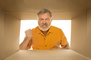 Image showing Senior man opening the biggest postal package isolated on white