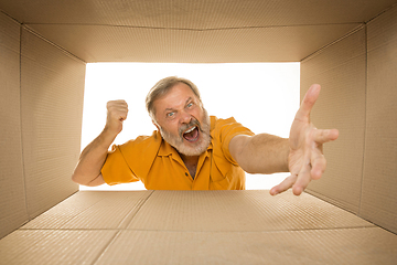 Image showing Senior man opening the biggest postal package isolated on white