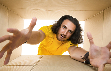 Image showing Young man opening the biggest postal package isolated on white