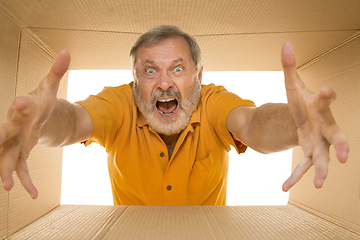 Image showing Senior man opening the biggest postal package isolated on white