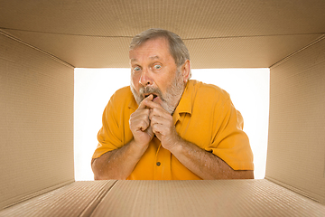 Image showing Senior man opening the biggest postal package isolated on white