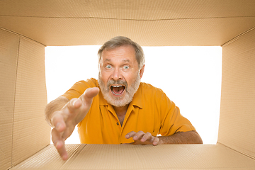 Image showing Senior man opening the biggest postal package isolated on white