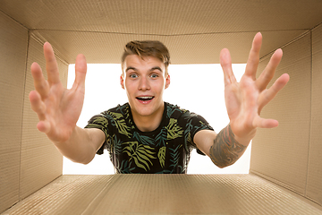 Image showing Young man opening the biggest postal package isolated on white