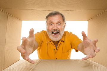 Image showing Senior man opening the biggest postal package isolated on white