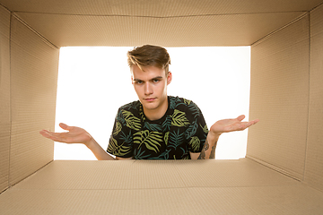 Image showing Young man opening the biggest postal package isolated on white