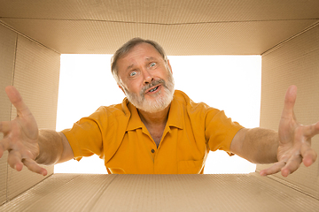 Image showing Senior man opening the biggest postal package isolated on white