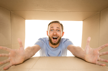 Image showing Young man opening the biggest postal package isolated on white