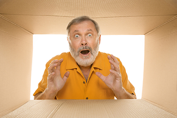 Image showing Senior man opening the biggest postal package isolated on white