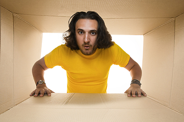 Image showing Young man opening the biggest postal package isolated on white