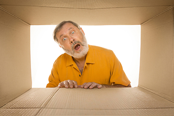 Image showing Senior man opening the biggest postal package isolated on white