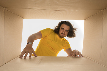 Image showing Young man opening the biggest postal package isolated on white