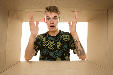 Image showing Young man opening the biggest postal package isolated on white