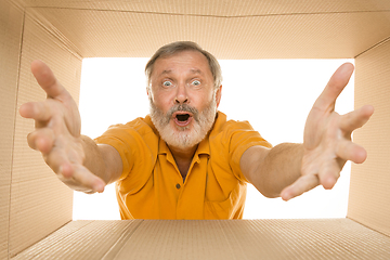 Image showing Senior man opening the biggest postal package isolated on white