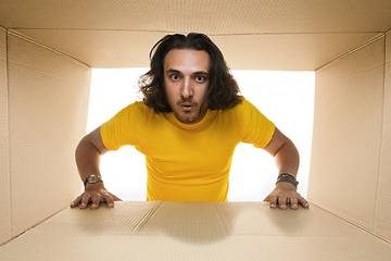 Image showing Young man opening the biggest postal package isolated on white