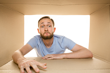 Image showing Young man opening the biggest postal package isolated on white