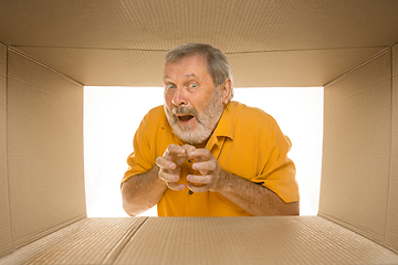 Image showing Senior man opening the biggest postal package isolated on white