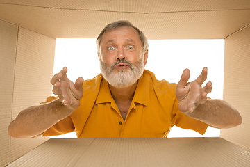 Image showing Senior man opening the biggest postal package isolated on white