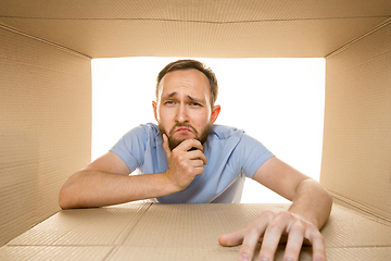 Image showing Young man opening the biggest postal package isolated on white