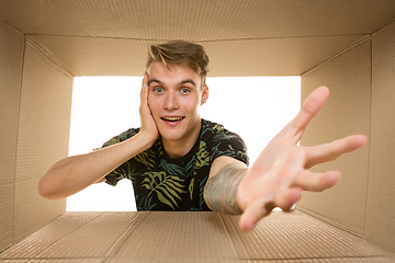 Image showing Young man opening the biggest postal package isolated on white