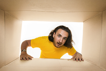 Image showing Young man opening the biggest postal package isolated on white