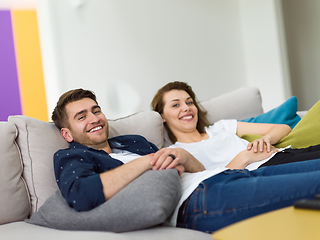 Image showing Portrait of young 25s just married couple in love posing photo shooting seated on couch in modern studio apartments