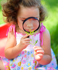 Image showing Young girl is looking at flower through magnifier