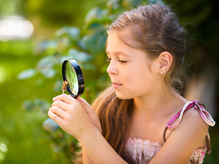 Image showing Young girl is looking at flower through magnifier