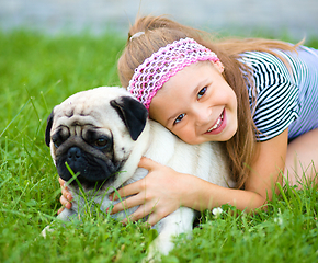 Image showing Little girl and her pug dog on green grass