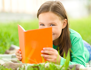 Image showing Little girl is reading a book outdoors