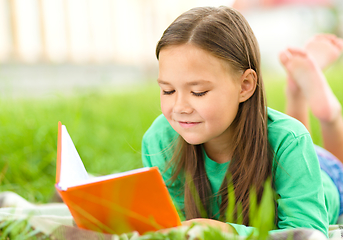 Image showing Little girl is reading a book outdoors