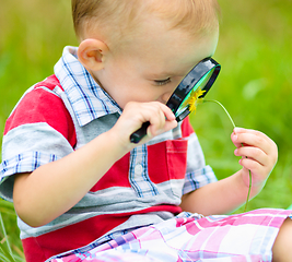 Image showing Young boy is looking at flower through magnifier