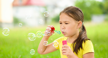 Image showing Little girl is blowing a soap bubbles