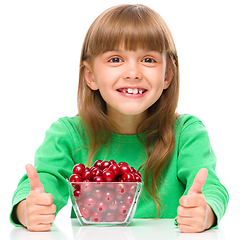 Image showing Cute girl is eating cherries showing thumb up sigh