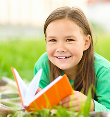 Image showing Little girl is reading a book outdoors