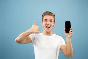 Image showing Caucasian young man\'s half-length portrait on blue background