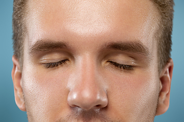 Image showing Caucasian young man\'s close up portrait on blue background