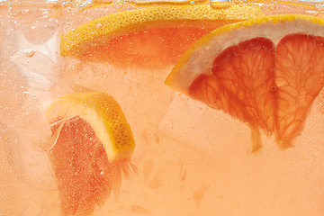 Image showing Close up view of the lemon and grapefruit slices in lemonade on background