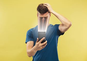 Image showing Young man engaged by gadget and social media isolated on yellow background