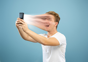 Image showing Young man engaged by gadget and social media isolated on blue background