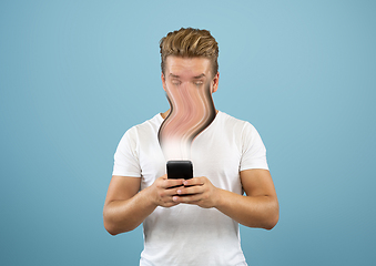 Image showing Young man engaged by gadget and social media isolated on blue background