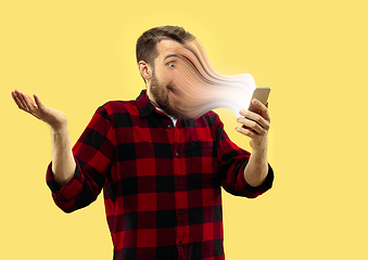 Image showing Young man engaged by gadget and social media isolated on yellow background