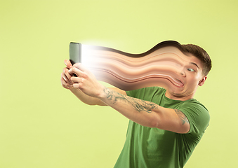 Image showing Young man engaged by gadget and social media isolated on green background