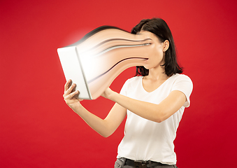 Image showing Young woman engaged by gadget and social media isolated on red background