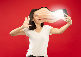 Image showing Young woman engaged by gadget and social media isolated on red background