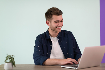 Image showing Smiling young man freelancer using laptop studying online working from home