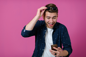 Image showing a young man wearing a blue shirt and sunglasses using a smartphone