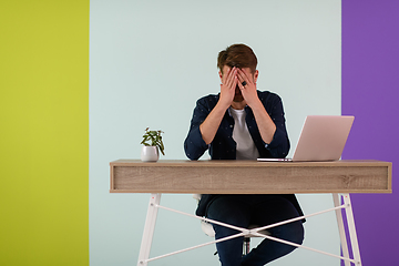 Image showing disappointed and annoyed man sitting at a table and looking at a laptop