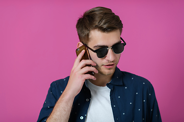 Image showing a young man wearing a blue shirt and sunglasses using a smartphone