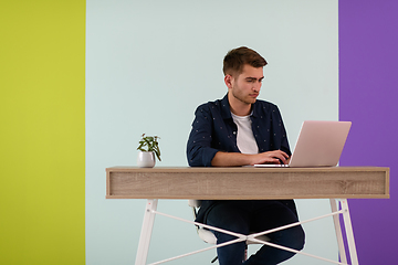 Image showing Smiling young man freelancer using laptop studying online working from home