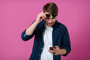 Image showing a young man wearing a blue shirt and sunglasses using a smartphone